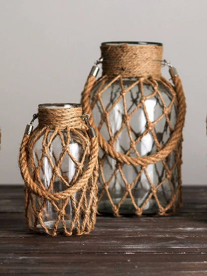 A hand‑woven hemp rope glass vase — a clear glass vessel wrapped in natural hemp fiber. Perfect for dried flowers, it adds texture and warm, rustic charm. Ideal for boho, Nordic, or minimalist interiors.